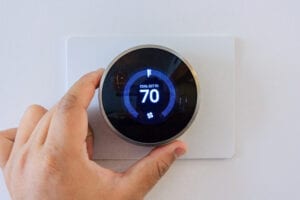 Hand,adjusting,air,conditioner,button,at,70,degree,fahrenheit,in